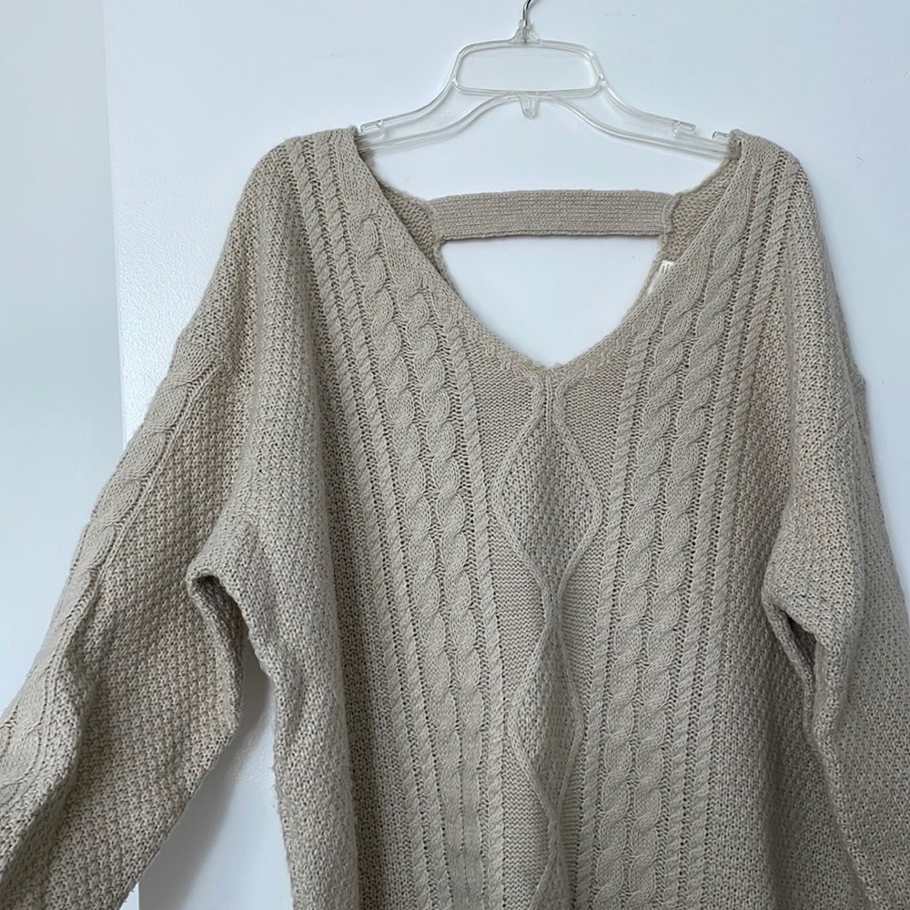 Cream / beige colored sweater. Strap across the back